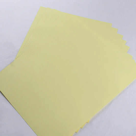 A stack of A4-sized, light yellow adhesive backing sheets for use in DIY crafting projects.