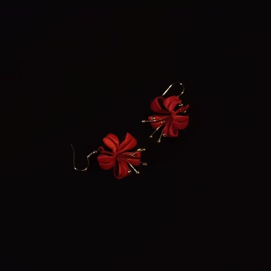 A close-up shot of the handcrafted red Chanhua flower earrings with 925 sterling silver hooks on a black background.