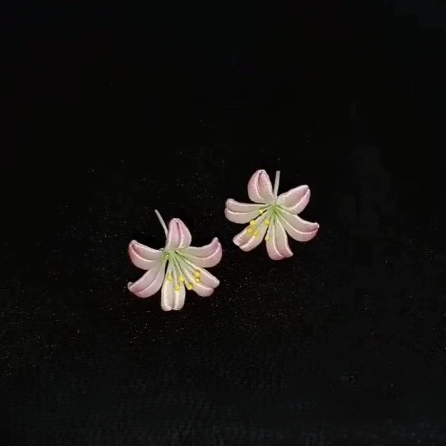 Close-up of a pair of handmade Chanhua earrings, highlighting the detailed ribbon work and 925 sterling silver hooks.