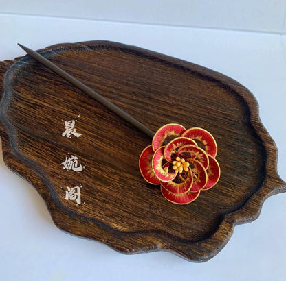 
Chanhua handmade red camellia hairpin with gold edge petals and yellow stamens, displayed on a dark wood tray