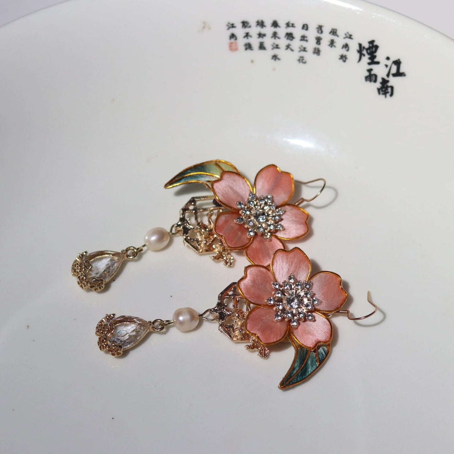 Handmade Ronghua pink camellia drop earrings in mulberry silk velvet with zircon crystal, pearl, and green leaf accents on gold hooks